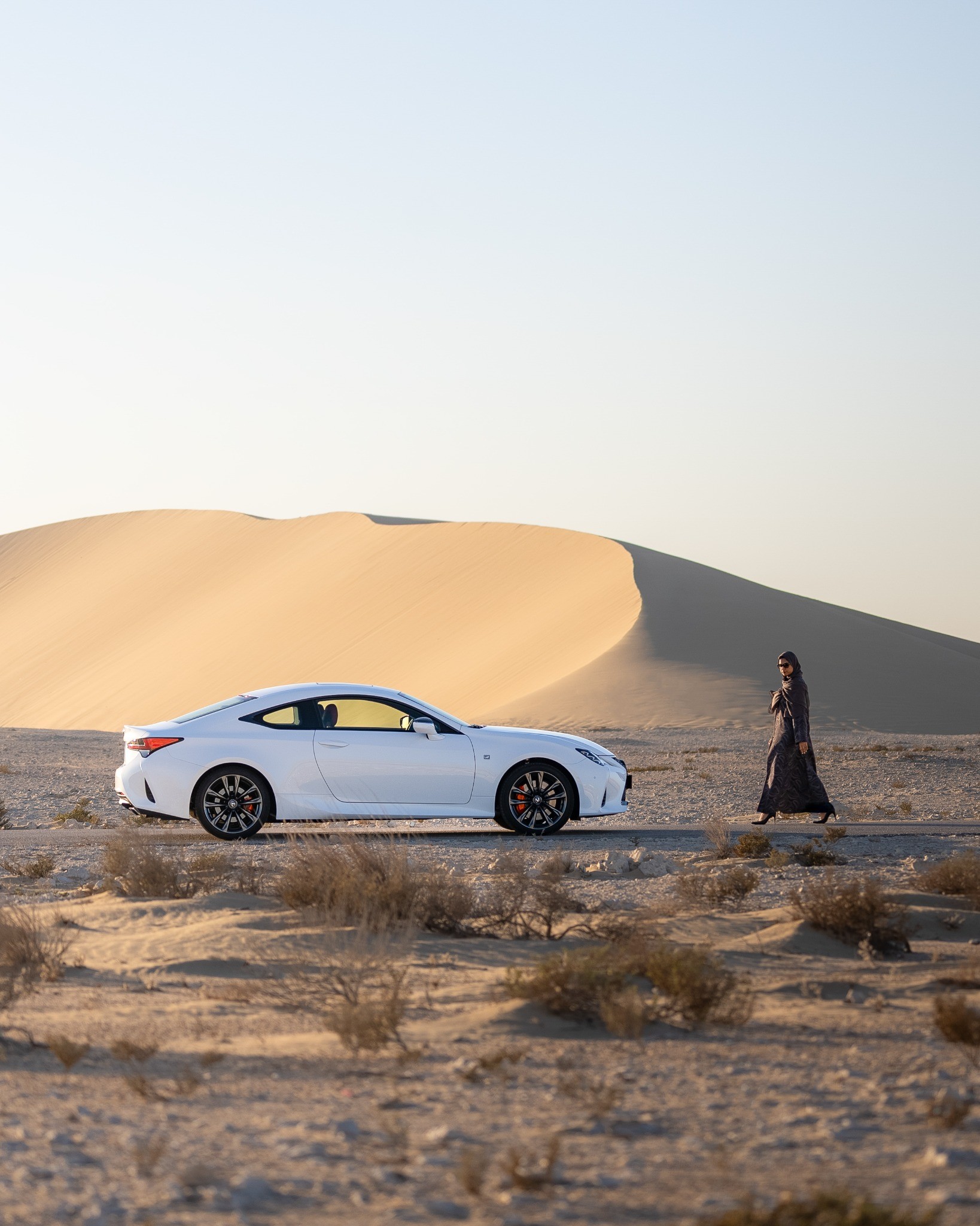 White sports coupe beside desert dunes